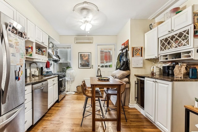 kitchen featuring white cabinetry, a wall mounted AC, light hardwood / wood-style floors, and stainless steel appliances