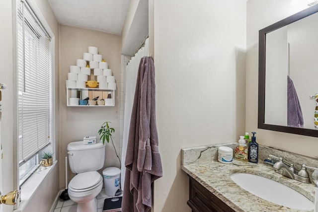 bathroom with toilet, vanity, tile patterned floors, and a healthy amount of sunlight