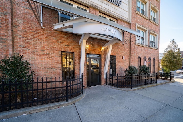 entrance to property with brick siding and fence