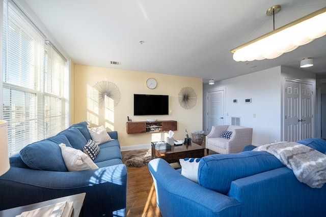 living room featuring visible vents, baseboards, and wood finished floors