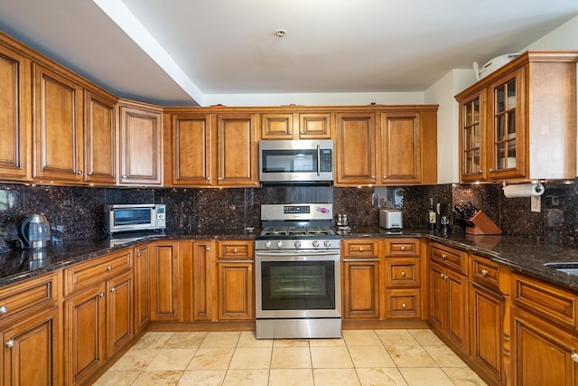 kitchen featuring glass insert cabinets, tasteful backsplash, appliances with stainless steel finishes, brown cabinets, and a toaster
