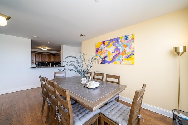 dining space featuring visible vents, baseboards, and wood finished floors