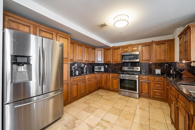 kitchen featuring brown cabinets, visible vents, backsplash, and appliances with stainless steel finishes