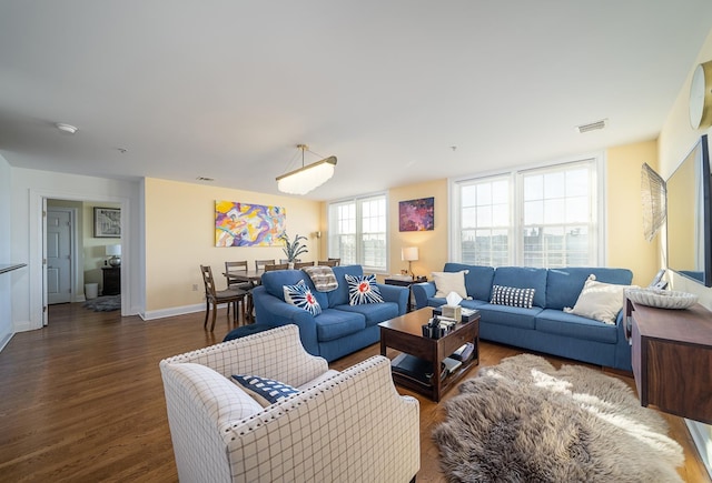 living area featuring wood finished floors, baseboards, and visible vents