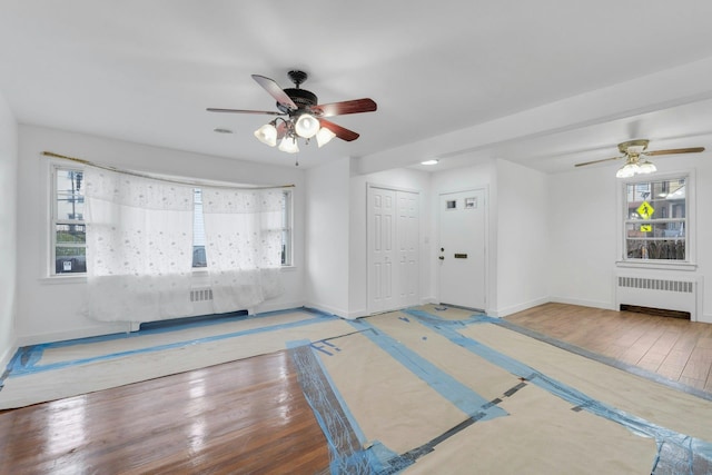 unfurnished living room featuring hardwood / wood-style flooring, ceiling fan, and radiator heating unit