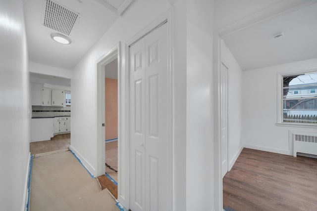 corridor with radiator heating unit and light hardwood / wood-style floors