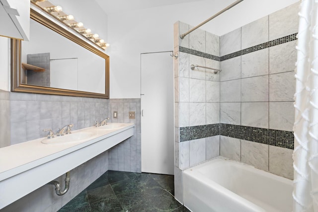 full bathroom featuring a sink, shower / bath combo with shower curtain, and tile walls