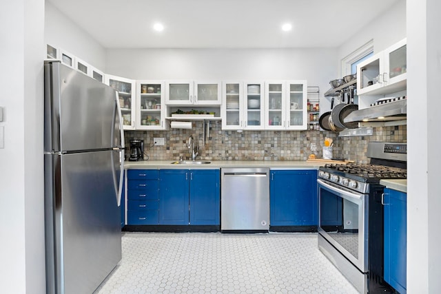 kitchen with blue cabinetry, light countertops, appliances with stainless steel finishes, a sink, and extractor fan