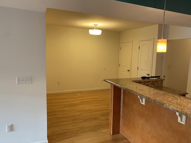 612 Palisade Ave, Jersey City, NJ 07307 - kitchen featuring baseboards, dark stone countertops, light wood-style floors, a breakfast bar area, and pendant lighting