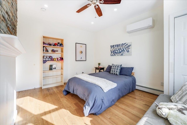 bedroom featuring ceiling fan, an AC wall unit, hardwood / wood-style floors, and baseboard heating