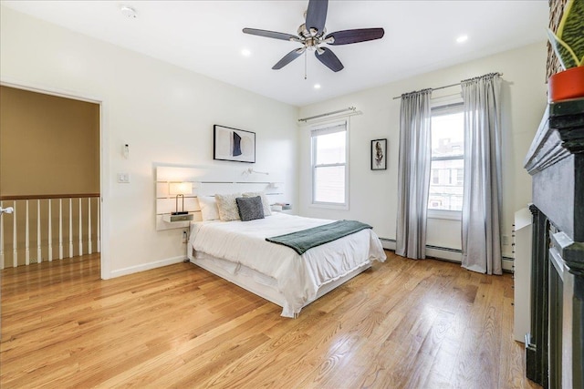 bedroom with ceiling fan, baseboard heating, and light wood-type flooring