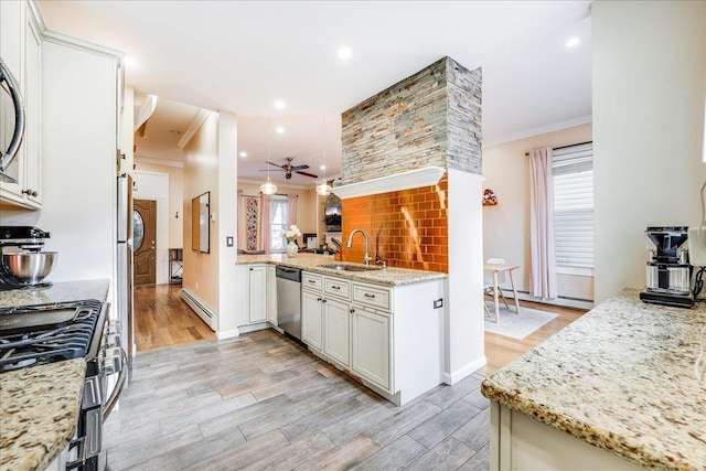 kitchen featuring light stone countertops, baseboard heating, stainless steel appliances, sink, and ornamental molding