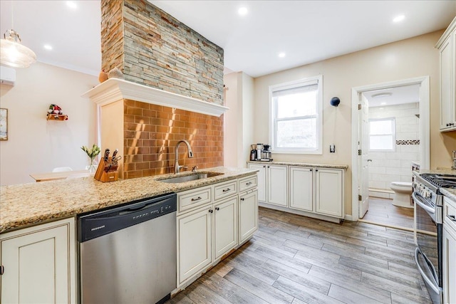 kitchen featuring hanging light fixtures, sink, light wood-type flooring, light stone countertops, and stainless steel appliances