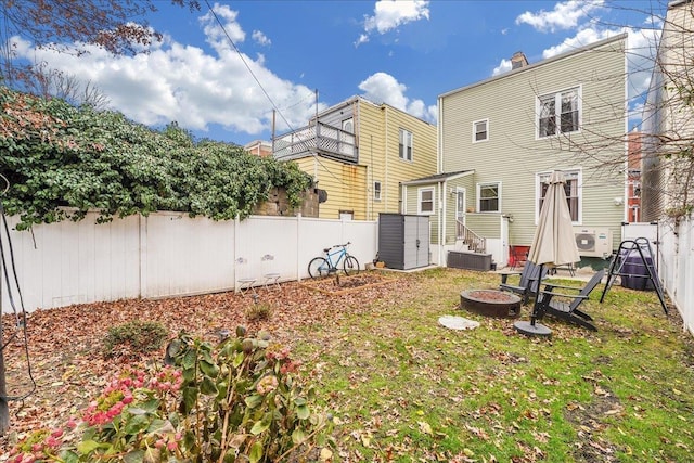 back of property with a fire pit, a yard, and ac unit