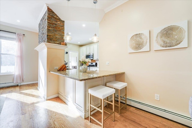 kitchen with kitchen peninsula, pendant lighting, appliances with stainless steel finishes, light stone countertops, and a breakfast bar area