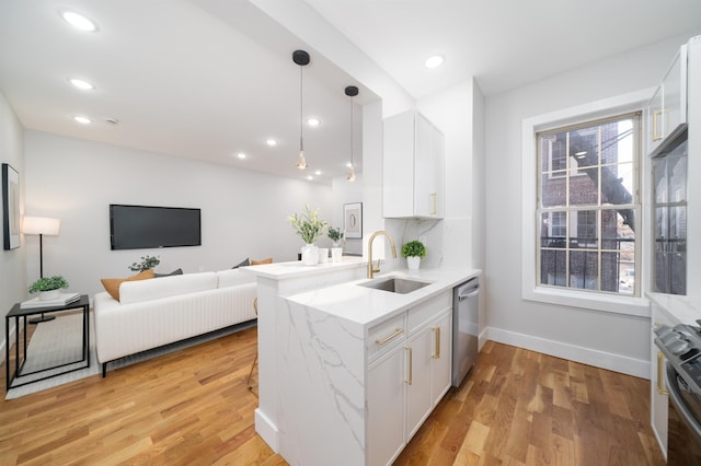 kitchen featuring stainless steel appliances, white cabinetry, sink, and kitchen peninsula