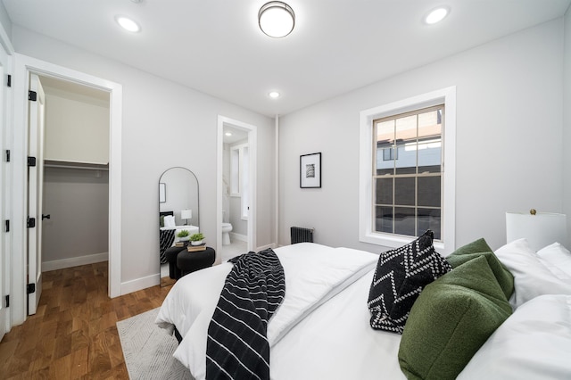 bedroom with connected bathroom, a spacious closet, dark hardwood / wood-style flooring, and a closet