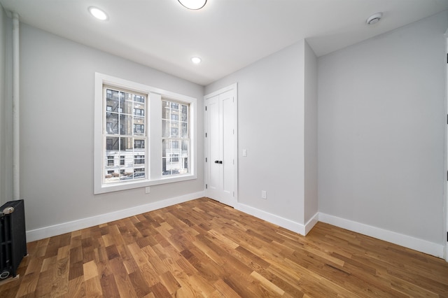 unfurnished room with wood-type flooring and radiator heating unit