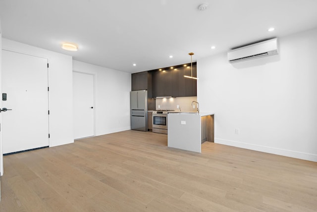 kitchen with stainless steel gas stove, a wall unit AC, modern cabinets, freestanding refrigerator, and light countertops