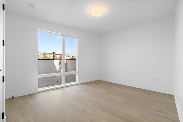 spare room featuring light wood-type flooring and baseboards