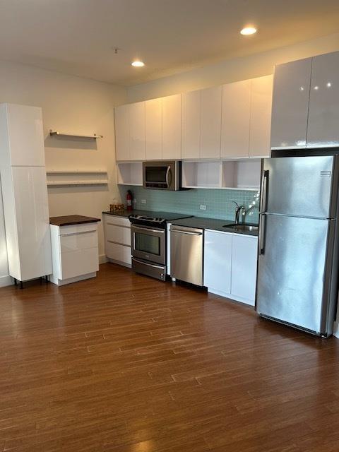 kitchen featuring white cabinetry, appliances with stainless steel finishes, dark hardwood / wood-style floors, backsplash, and sink