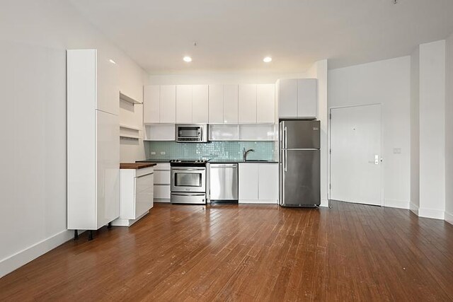 kitchen with dark wood-type flooring, appliances with stainless steel finishes, white cabinetry, and sink