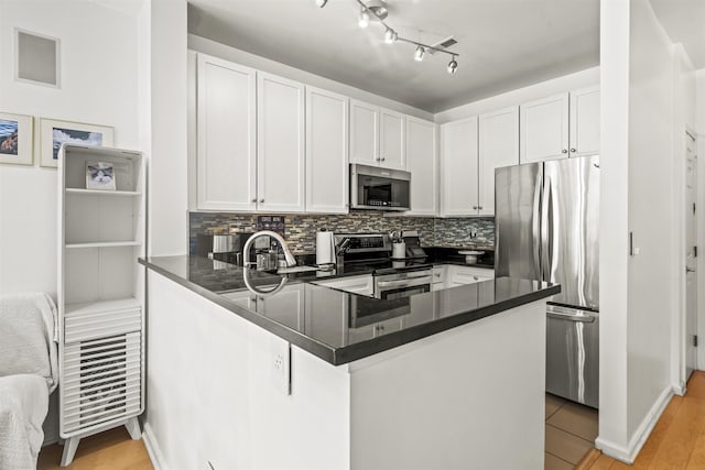 24 Ave At Port Imperial Unit 328, West New York, NJ 07093 - kitchen featuring dark countertops, appliances with stainless steel finishes, a peninsula, and white cabinets