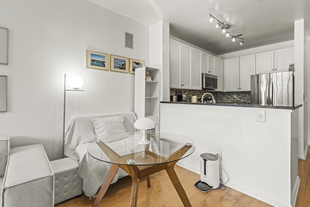 24 Ave At Port Imperial Unit 328, West New York, NJ 07093 - kitchen featuring dark countertops, appliances with stainless steel finishes, a peninsula, light wood finished floors, and tasteful backsplash
