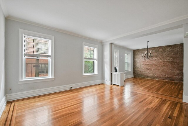 1000 Hudson St Unit 209, Hoboken, NJ 07030 - unfurnished living room with a chandelier, brick wall, healthy amount of natural light, light wood-style flooring, and radiator