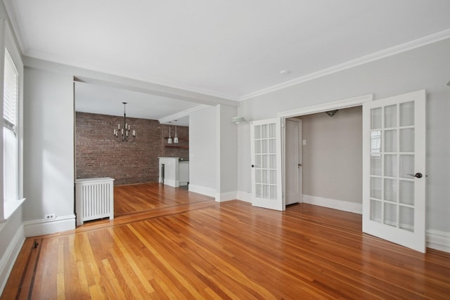 1000 Hudson St Unit 209, Hoboken, NJ 07030 - unfurnished living room with french doors, radiator, a chandelier, wood finished floors, and brick wall