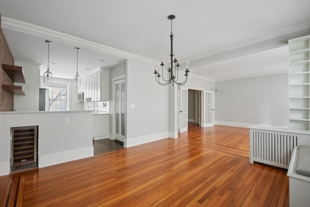 1000 Hudson St Unit 209, Hoboken, NJ 07030 - unfurnished living room with beverage cooler, hardwood / wood-style floors, a chandelier, ornamental molding, and radiator heating unit