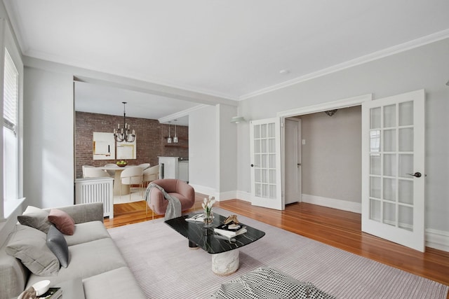 1000 Hudson St Unit 209, Hoboken, NJ 07030 - living room featuring french doors, wood finished floors, a chandelier, ornamental molding, and brick wall