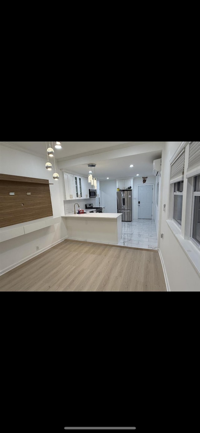 67 Winfield Ave, Jersey City, NJ 07305 - kitchen featuring stainless steel appliances, a peninsula, a wall unit AC, light countertops, and white cabinetry