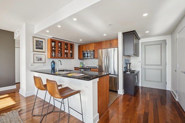 kitchen featuring sink, dark hardwood / wood-style flooring, a kitchen breakfast bar, kitchen peninsula, and stainless steel appliances