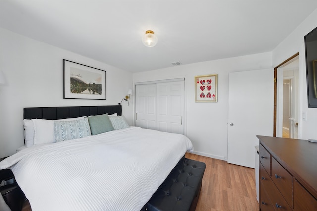 bedroom featuring light wood-style flooring, visible vents, and a closet