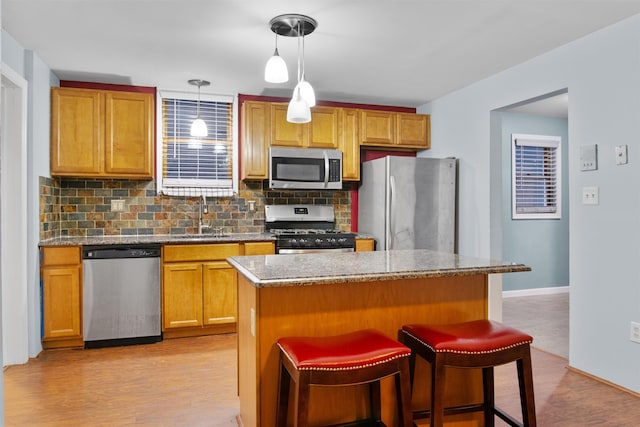 kitchen with a sink, backsplash, a breakfast bar area, and appliances with stainless steel finishes