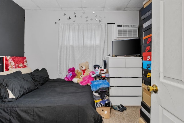bedroom with a drop ceiling and an AC wall unit