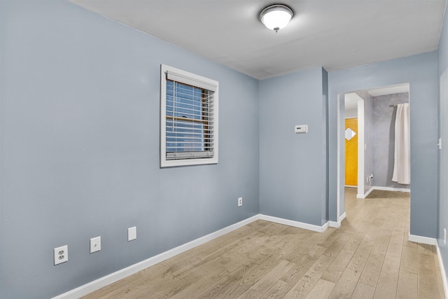 empty room featuring baseboards and light wood-type flooring