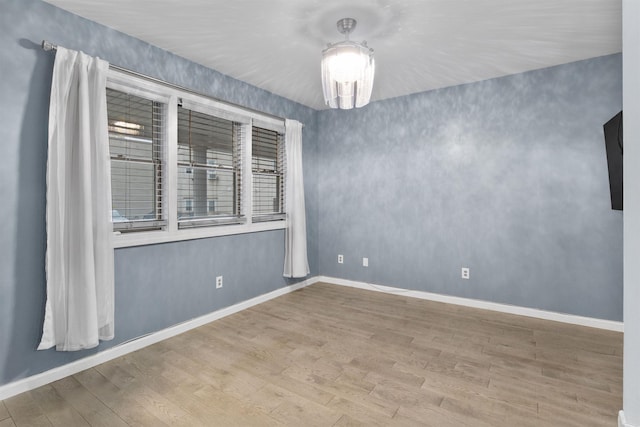 unfurnished room with baseboards and wood finished floors