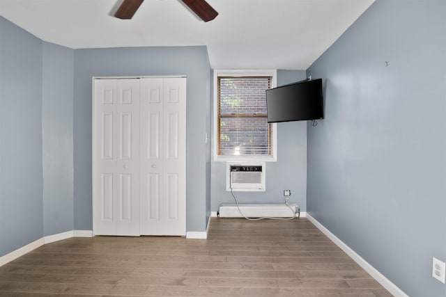 interior space with wood finished floors, baseboards, ceiling fan, and an AC wall unit