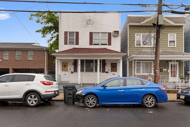 townhome / multi-family property featuring a porch and an AC wall unit