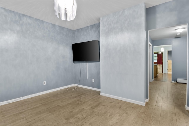 empty room featuring baseboards, baseboard heating, and wood finished floors