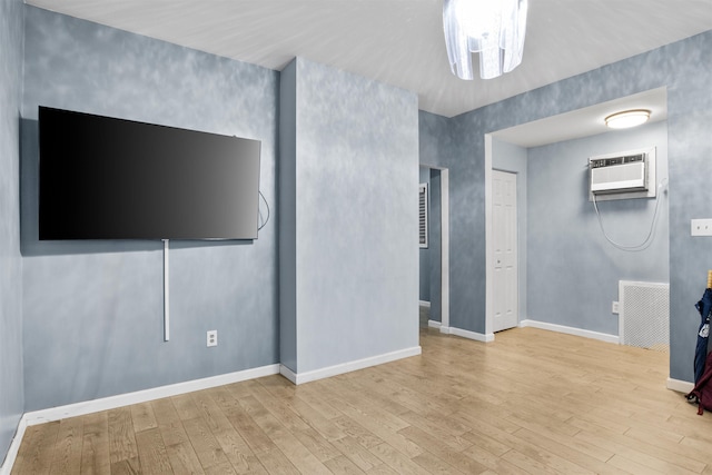 unfurnished living room with visible vents, wood finished floors, baseboards, and a wall mounted AC