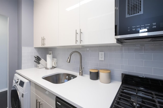 kitchen with washer / clothes dryer, stainless steel microwave, white cabinets, light countertops, and backsplash