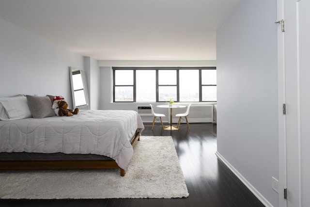 bedroom with dark wood-type flooring, a wall mounted AC, and baseboards