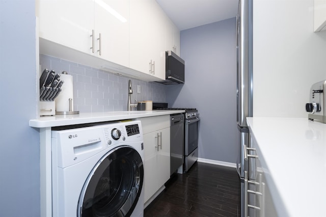 clothes washing area with washer / clothes dryer, dark wood-type flooring, and baseboards