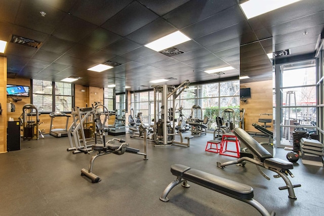 gym featuring wooden walls and a drop ceiling