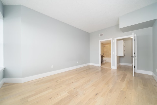 unfurnished bedroom with light hardwood / wood-style flooring, a textured ceiling, and ensuite bathroom