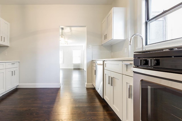 kitchen with backsplash, dishwashing machine, white cabinets, and hanging light fixtures