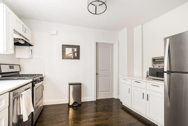 kitchen with white cabinets, dark hardwood / wood-style floors, stainless steel appliances, and tasteful backsplash